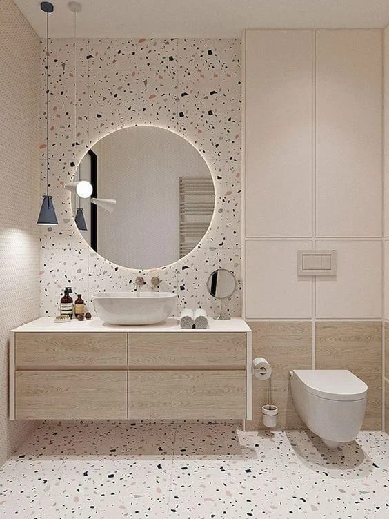 Bathroom modern dengan lantai dan backsplash terazzo, vanity kayu, cermin bulat, dan toilet dinding